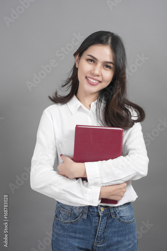 Portrait of woman University student holding book in studio grey background