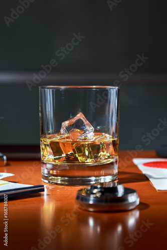 Fototapeta Naklejka Na Ścianę i Meble -  glass of Scotch with ice on the desktop among contracts and documents