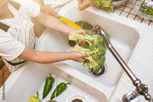 Father with son washes vegetables before eating photo