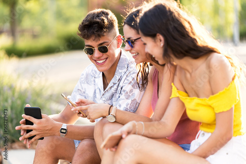 Group of young hipster friends using smart phone in an urban area.