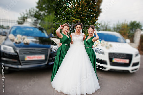 Attractive bride posing with bridesmaids next to the wedding suvs. © AS Photo Family