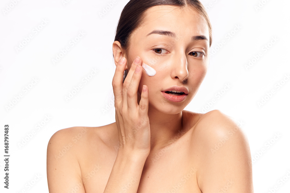 Beautiful young woman on white isolated background applies cosmetic face cream Beautiful young woman on white isolated background applies cosmetic face cream