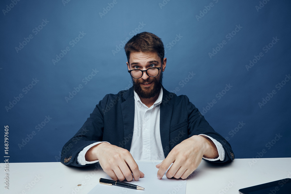 Business man with a beard on a blue background working at his desk in the office Business man with a beard on a blue background working at his desk in the office