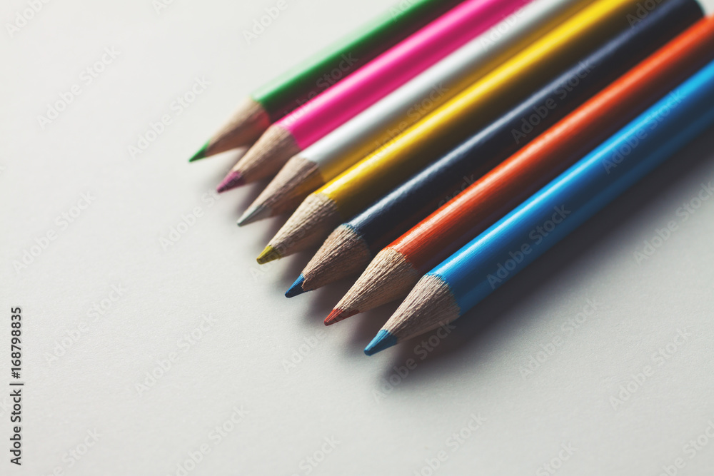 Close-up of a group of multicolored pencils on a white surface Close-up of a group of multicolored pencils on a white surface