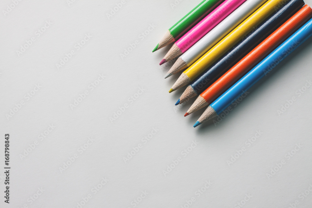 Close-up of a group of multicolored pencils on a white surface Close-up of a group of multicolored pencils on a white surface