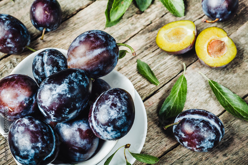 Fresh plums with leaveson a dark wood background. toning. selective focus photo