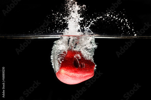 A apple falls deeply under water with a big splash. photo