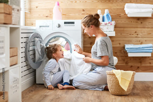 Fotografiet Happy family mother housewife and child   in laundry with washing machine