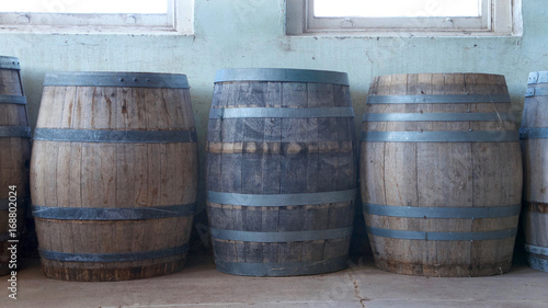 Old wood barrels lining a worn weathered wall in the basement of an old building. Used for food storage in early American history