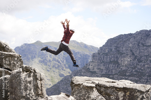 A male hiker jumps with joy in a scenic mountainous terrain photo