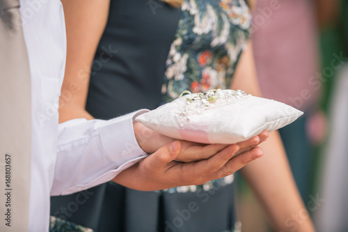 Newlyweds exchange rings, groom hold bride's hand.