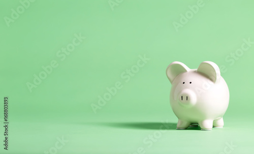 White piggy bank with glasses on a muted green background