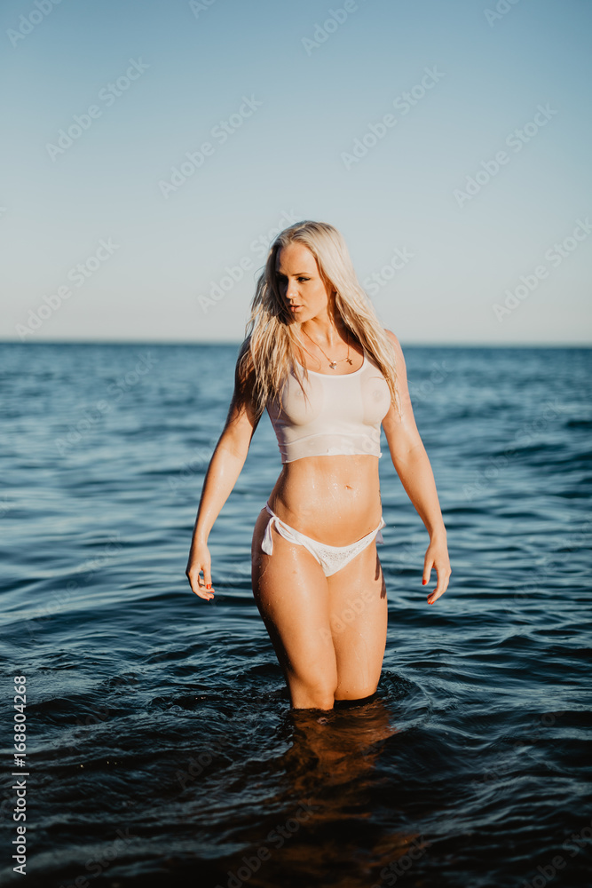 Sexy woman in wet t-shirt walking in water at beach over sea. Summer time  Stock Photo | Adobe Stock