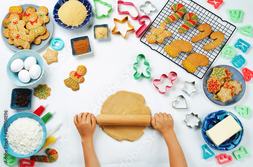 Children's hands roll ginger dough with Gingerbread cookies and ingredients for baking