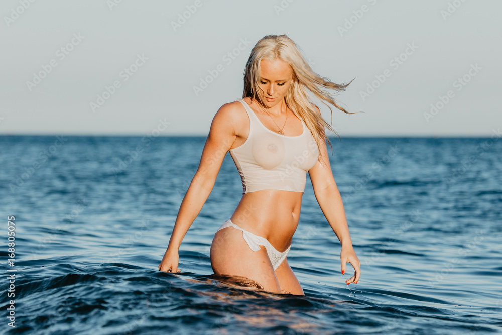 Sexy woman in wet t-shirt playing on water at beach over sea. Summer time  Stock Photo | Adobe Stock