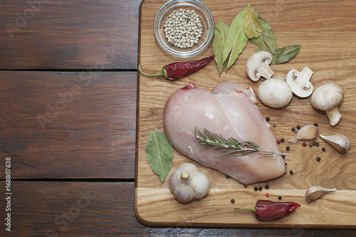 Fresh meat. Chicken fillet with chili, spices and rosemary on a cutting board. photo