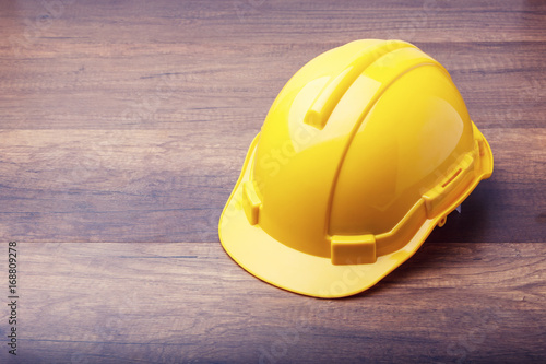 The yellow hard hat construction on wooden board