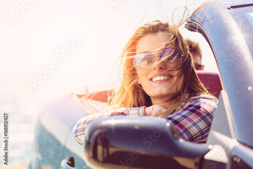 Fotografía Front view of woman sitting in cabriolet putting hand on door looking away on background of sea