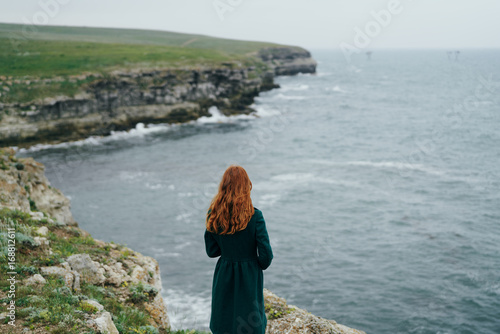 Beautiful young woman on a cliff above the sea, nature