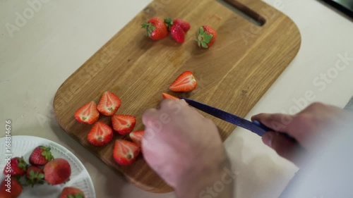 Man cuts strawberries clsoe up. photo