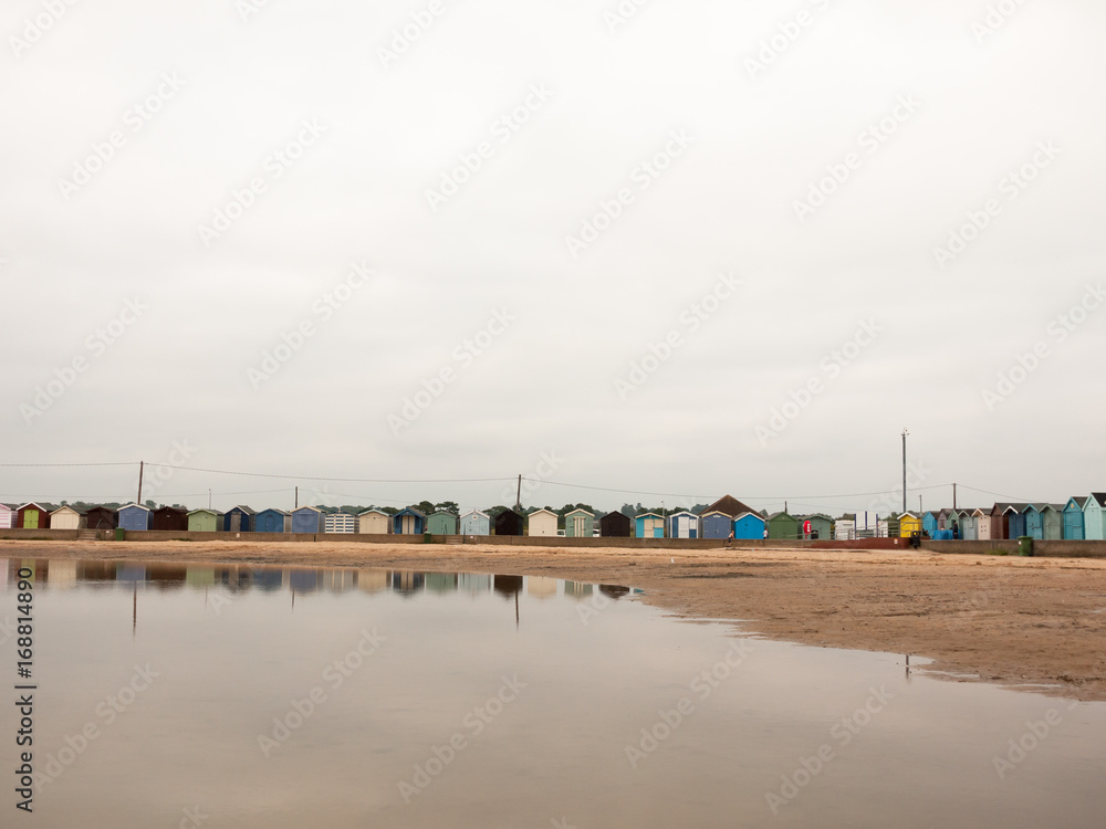 beautiful scene of beach huts with reflections in water in front