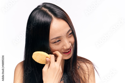 Beautiful young woman on white isolated background holds a sponge for make-up removal, asian