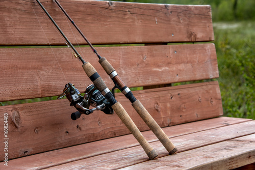 Two fishing poles on a bench