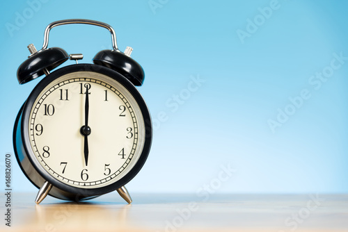 black alarm clock on the table and blue background