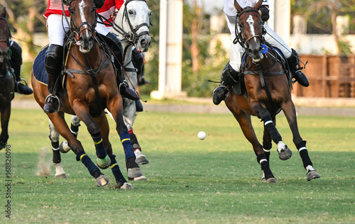 Ball is floating in the air during a polo match.