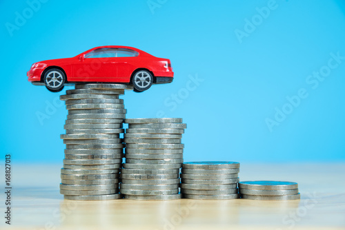 red miniature car model on stack of coins