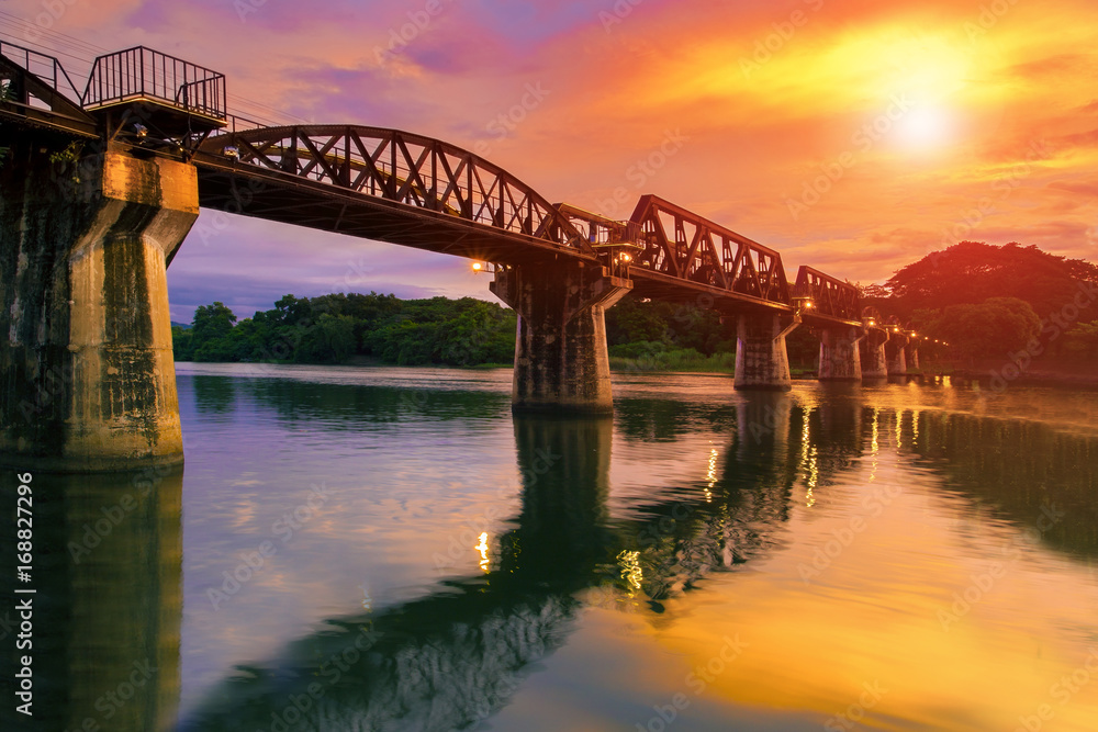 Naklejka premium colorful twilight time of river khaw bridge in kanchanaburi most popular world war II history traveling destination in western of thailand