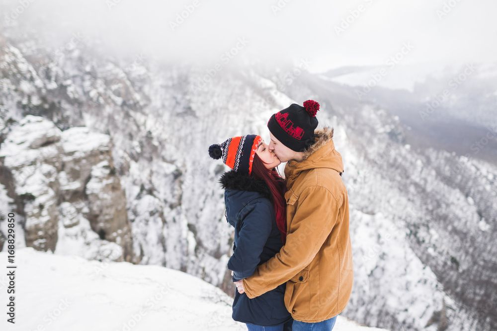 Couple in love walking in winter mountains. Beautiful view with snow, rocks and fog