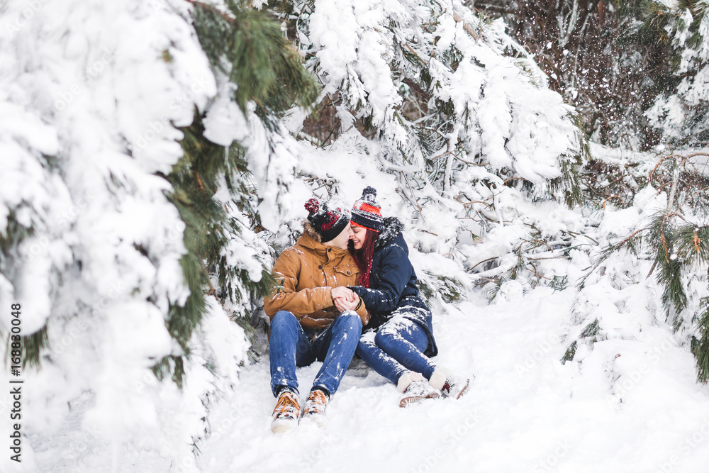 Сouple having fun and throwing snow in winter forest. A lot of snow around