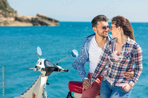 Couple sitting on motor scooter looking at each other photo