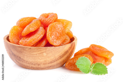 Dried apricots in a wooden bowl with mint leaves isolated on white background