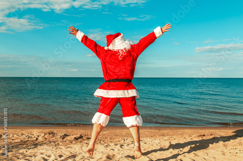 Santa Claus jumps on the beach.