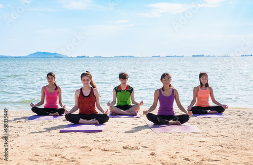 Yoga class at sea beach in sunny day ,Group of people doing lotus pose with clam relax emotion,Meditation pose,Wellness and Healthy balance lifestyle