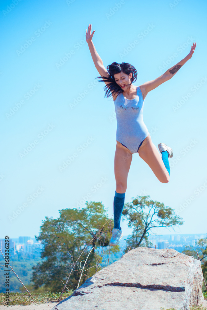 Exercises at city park. Lady exercising outdoors. Concept of healthy lifestyle. Portrait of athletic young woman resting on a nature. Beautiful woman at the park on a sunny day, city background Exercises at city park. Lady exercising outdoors. Concept of healthy lifestyle. Portrait of athletic young woman resting on a nature. Beautiful woman at the park on a sunny day, city background