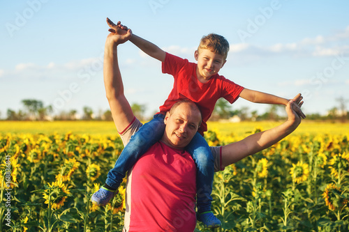 father with child in a field of blooming sunflowers , father's day
