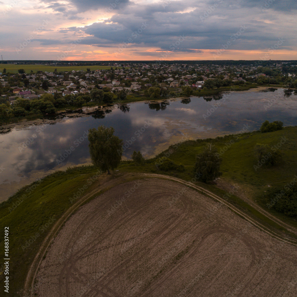 Beautiful panorama of countryside with a beautiful lake at sunset. Aerial view of scenic landscape in Ukraine, Central Europe.