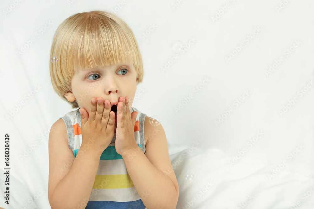 Surprised little boy sitting in white bed Surprised little boy sitting in white bed