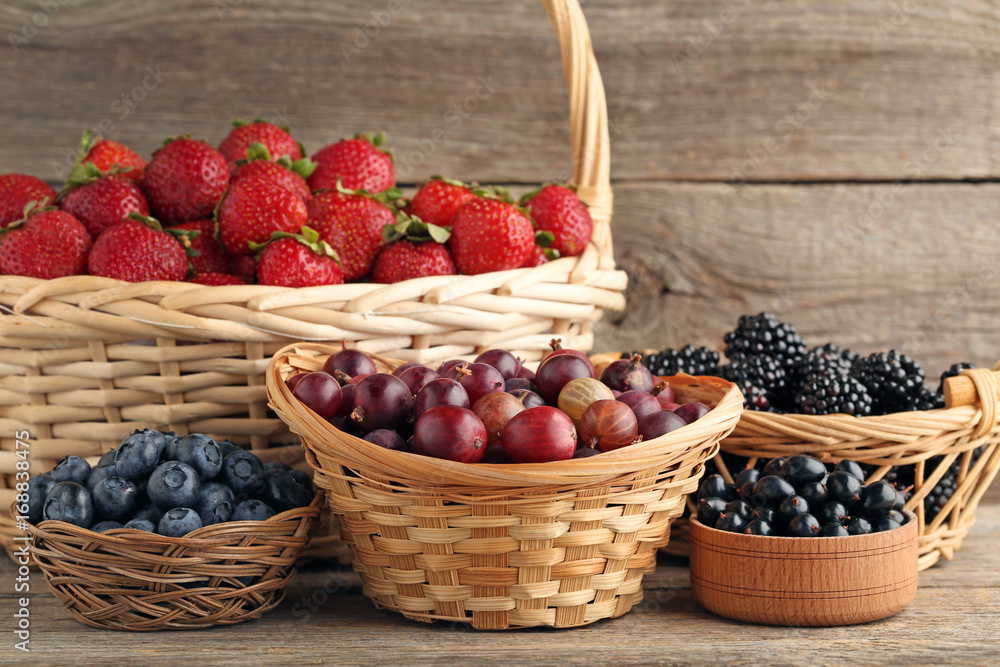 Ripe and sweet berries in baskets on wooden table Ripe and sweet berries in baskets on wooden table