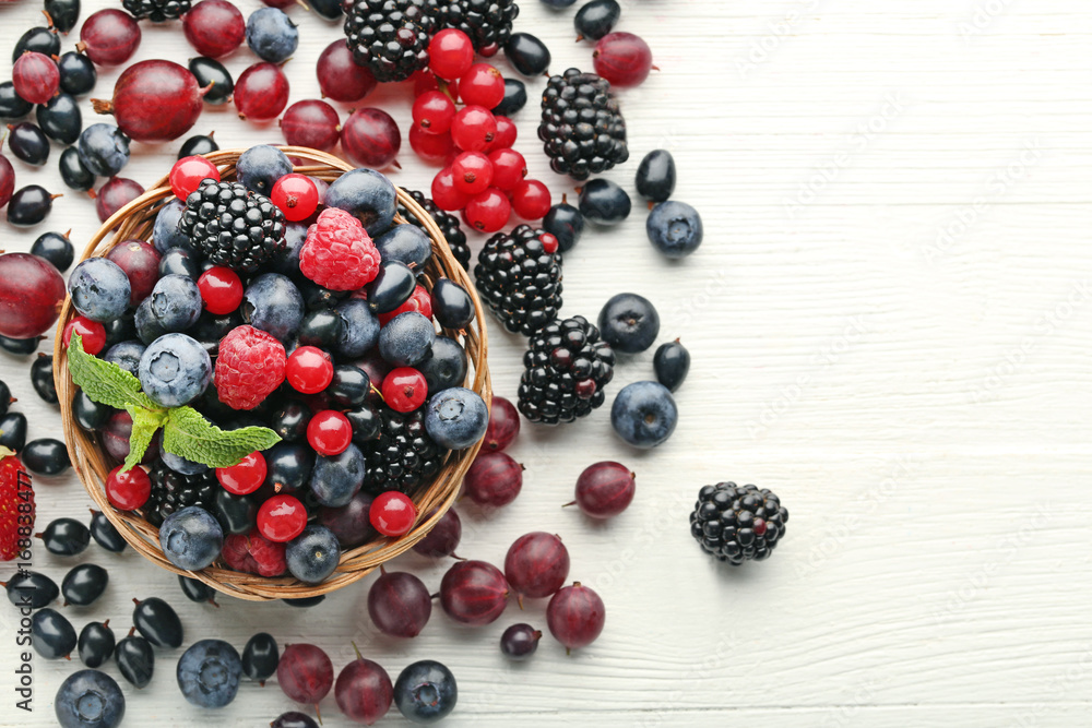 Ripe and sweet berries in basket on white wooden table Ripe and sweet berries in basket on white wooden table