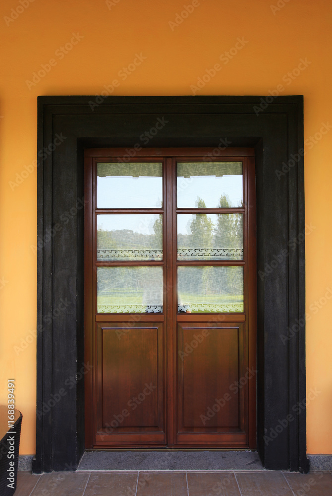 Rural italian house with wooden door and orange wall Rural italian house with wooden door and orange wall