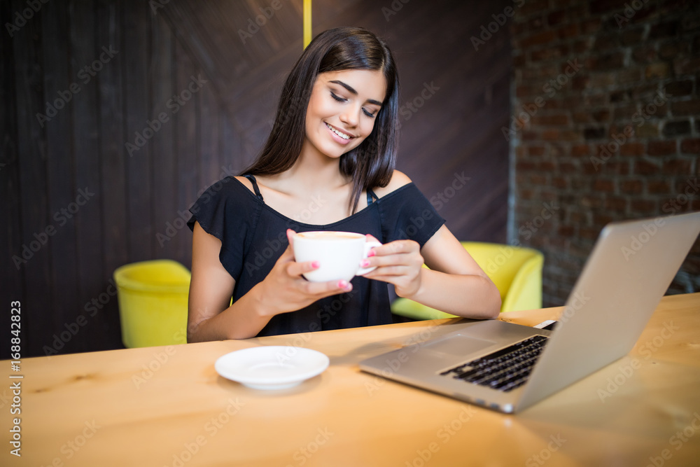 Young woman drinking coffee and using computer in cafe Young woman drinking coffee and using computer in cafe