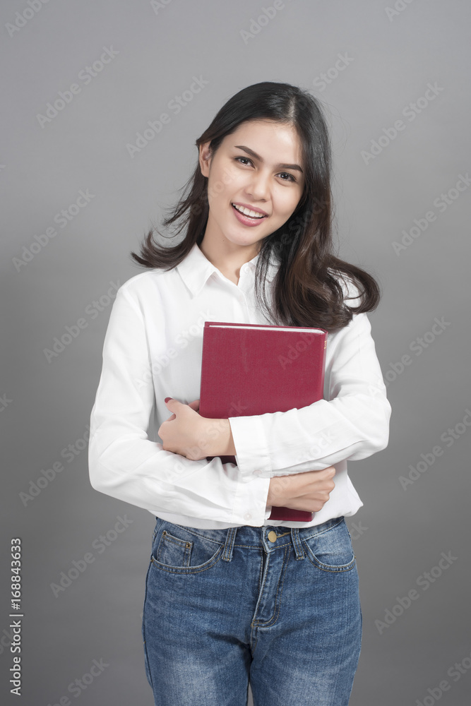 Portrait of woman University student holding book in studio grey background Portrait of woman University student holding book in studio grey background