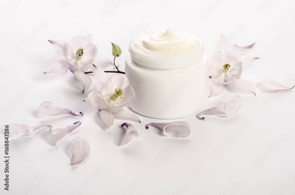 Cute flowers and petals and a jar of natural body cream isolated on white background Cute flowers and petals and a jar of natural body cream isolated on white background