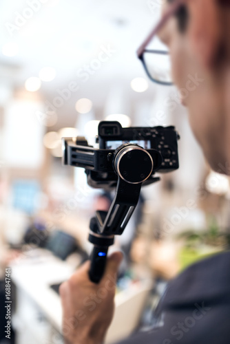 Adult professional videographer shooting using new steadycam. He looking at result on display screen © stockcrafter