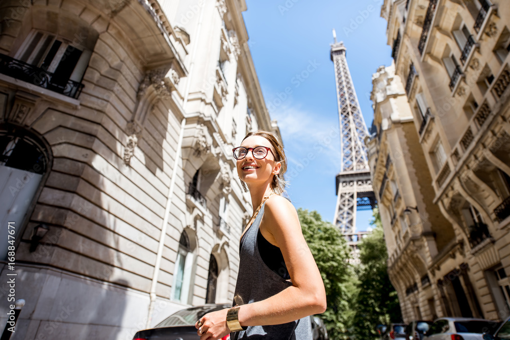 Fototapeta premium Lifestyle portrait of a young stylish woman walking the street with eiffel tower on the background in Paris