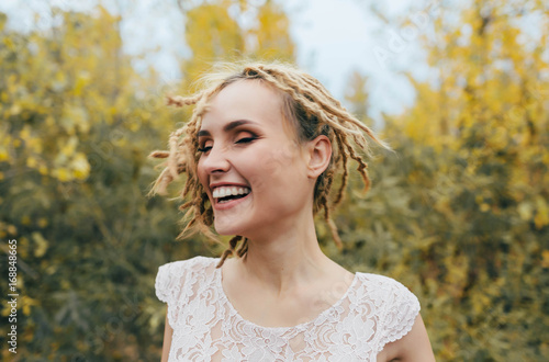 A girl is spinning and shaking her hair. Image in motion. Close-up portrait of a happy bride with dreadlocks. Artwork.